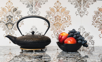 Tea Pot and bowl of fruit against a tile background