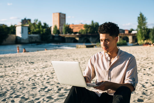 Afro And Black Man Working With His Laptop Or Computer On The Beach