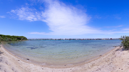 Salento coast: view of Porto Cesareo town in Apulia, Italy. Sandy beach in  the Big Island (or Isola Grande) Nature Reserve Islet located in front of harbor of Porto Cesareo.