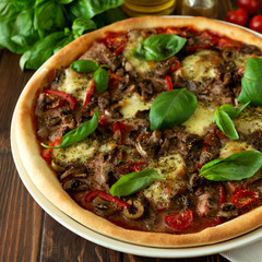 Delicious italian pizza and cherry tomatoes and basil on brown wooden background. Copy space.