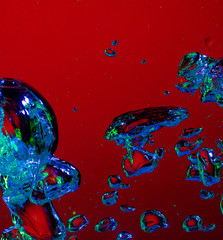 Close up view of the cold and fresh cola with bright bubbles in neon light. Texture of cooling summer's drink with macro bubbles on glass. Fizzing or floating up to top of surface, splashing fluid.