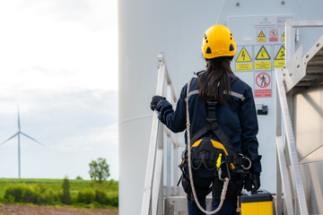 Asian woman Inspection engineer preparing and progress check of a wind turbine with safety in wind...
