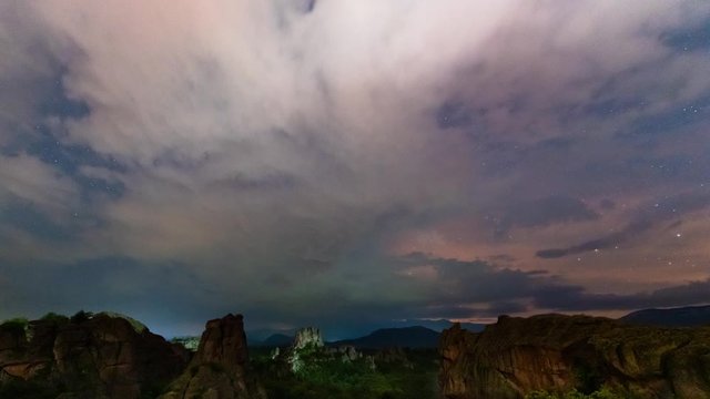 Amazing night time lapse with Milky Way galaxy, storm lightning, plane trails and meteor shower, during Perseid Stream over picturesque rock formation, Belogradchik rocks, Bulgaria