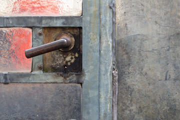 Close up of a old rusty door handle on a glass door in a abandoned greenhouse