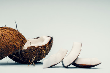 Parts of coconut on a colored background. Close up. Fresh ripe coconut broken into pieces.