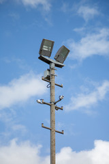 Floodlights above a football pitch with blue sky and clouds in the background