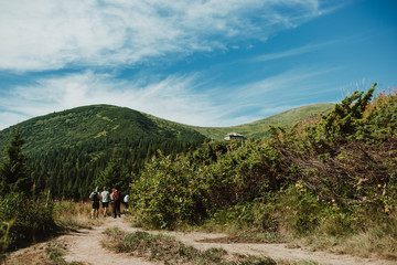 Fototapeta premium Silhouettes of a group of people with backpacks walking on a mountain road. Tourism concept
