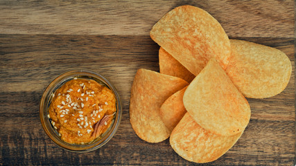 Potato chips on a wooden board with sauce. Snack, ready meal menu, junk food. Close up.