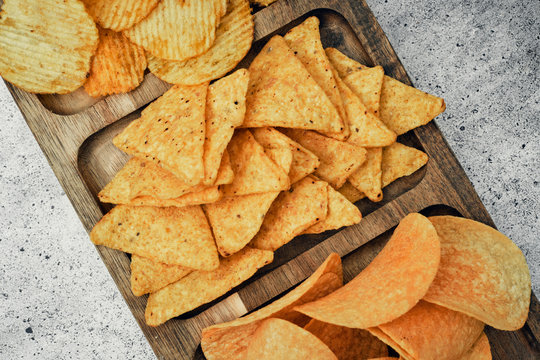 Chips, snacks and crackers on a wooden board. Fast food.