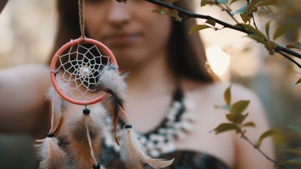 Young beautiful and mysterious woman holding dreamcatcher in the forest. No face, slow motion. High...
