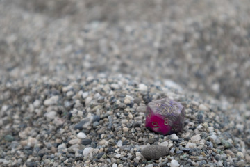 Grey Purple Pink Dungeon and Dragons dice with character sheets at the beach