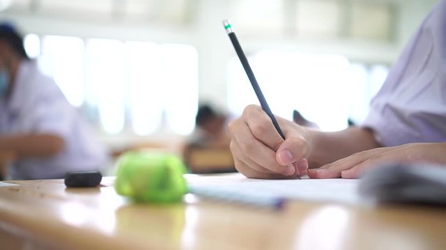 Student hand testing doing test exam with pencil drawing selected choices on answer sheet in school final exams at college or university. Taking multiple choice for assessment in examination classroom