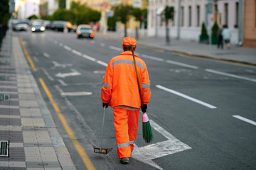 Male janitor with broom and dustpan, cleaning city from garbage. Man cleaner sweeping street with broom, municipal worker in uniform with broomstick and scoop for garbage in hands, cleaning service