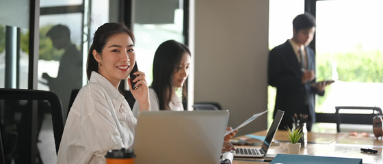 Portrait shot young businesswoman calling her phone and looking at camera.