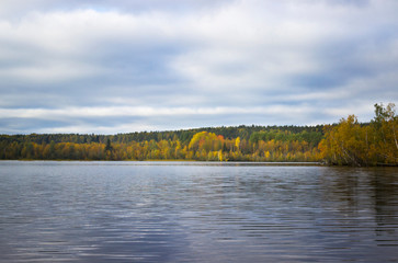 Orange autumn Sunny landscape with trees and clouds reflected in the lake
