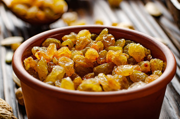 White Raisins in clay bowl on wooden kitchen table food background