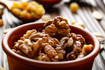 Walnuts in clay bowl on kitchen wooden table food background