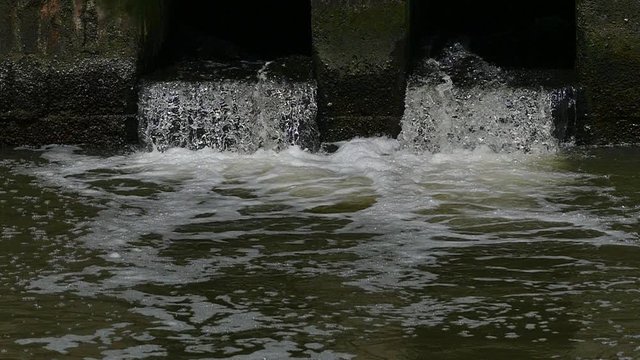 Dirty water flows from the pipe into the river