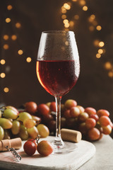 Composition with glass of wine and grape on brown background with blurred lights