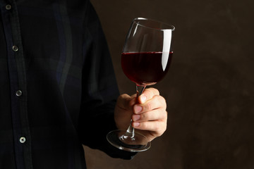 Man hold glass of wine on brown background