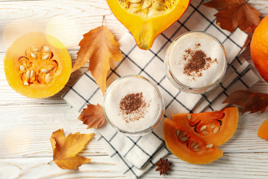 Composition with pumpkin latte on white wooden table