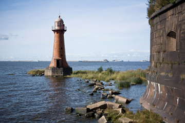 Old abandoned lighthouse near the shore on a sunny summer day.