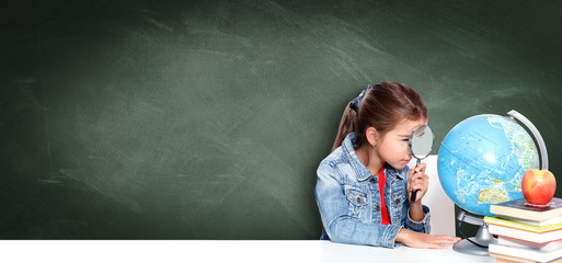 Curious little girl looking through magnifying glass on globe