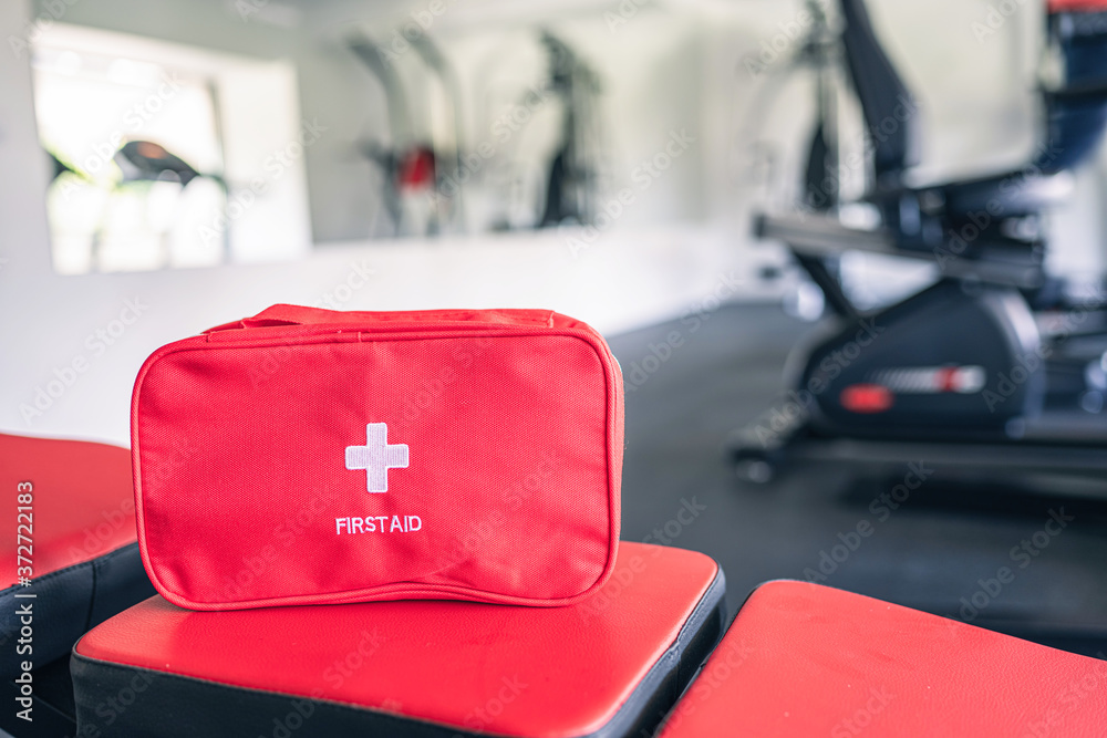 Wall mural First aid kit red box in the fitness gym opposite the sport equipment and  jogging simulators. Healthy lifestyle, safety and help concept