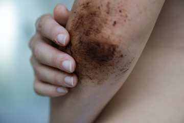 Naklejka premium DIY Coffee scrub. Beauty skin care. Young woman putting coffee scrub on dry elbow skin. 