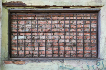 Brick wall behind bars in the window of the house. The destroyed brick wall of the building. Сoncept of the Jail Break and respect for Human Rights.