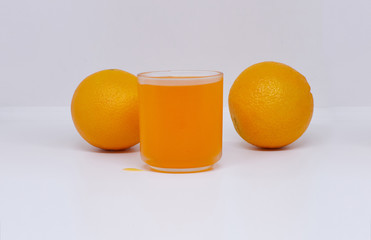 Orange juice in glass cup with orange on white background.