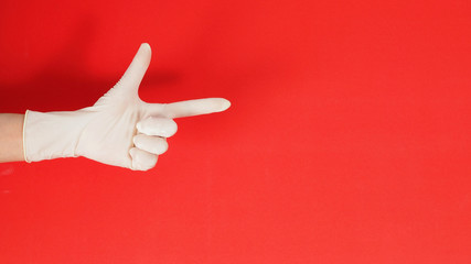 woman is point the finger up and wear surgical glove on red background.