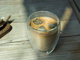 Ice cubes of coffee poured with milk. Iced coffee in a glass on a wooden table. Coffee cube iced. Ice frappe.