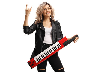 Female musician with a curly blond hair with a keytar synthesizer gesturing rock and roll sign