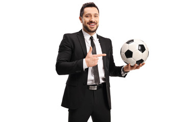 Professional man in a black suit holding a soccer ball and pointing