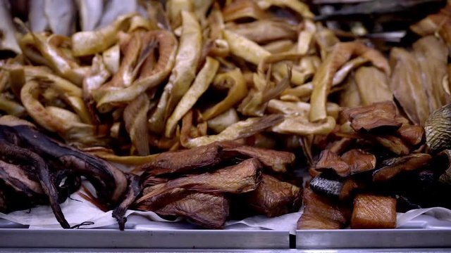 Variety of smoked sea fishes and other seafood on the counter in a fish shop, slow motion