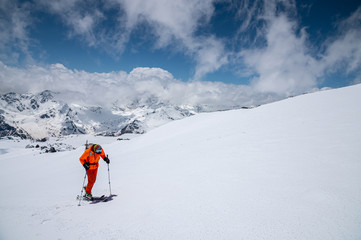 Naklejka na ściany i meble A skier in an orange suit skis in a mountain off-piste skiing in the northern caucasus of Mount Elbrus