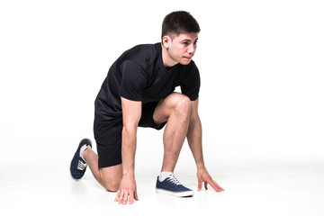 Full length portrait of a male athlete ready to run on white background