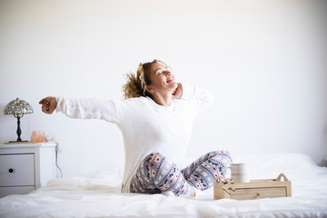 Beautiful woman wake up in the morning and do breakfast in the bed - bedroom life for healthy people waking up and getting ready to start a new day - white image and background with people