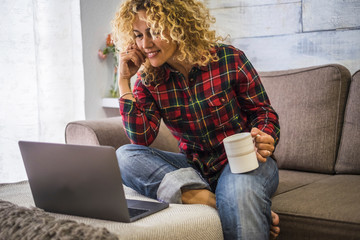 Portrait of caucasian adult beautiful woman at home use a laptop computer sitting on the couch - concept of video call conference and smart work - people and connection - watching movie