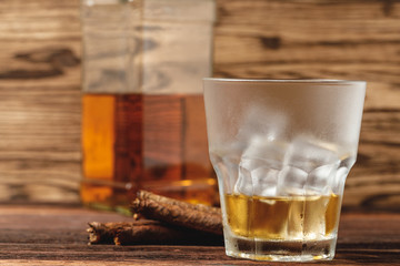 Glass of whiskey and rolled cigars on wooden table