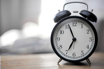 Vintage black alarm clock on bedroom. Morning time background concept with copy space.