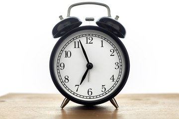 Vintage black alarm clock on wooden table isolated on white background