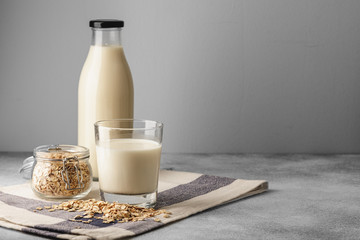 Vegan oat milk with oat flakes close up - obrazy, fototapety, plakaty