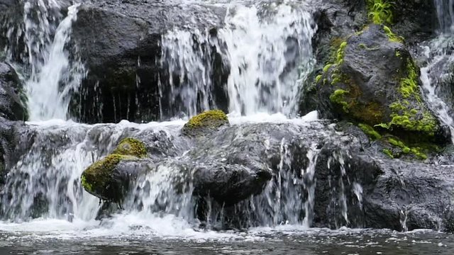 Slow motion waterfall over dark rocks