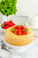 Cottage cheese grated casserole with crumb and fresh strawberries on top on a white plate on a light wooden background. Traditional Russian cake. Vertical, copy space.