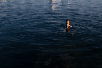 Young beautiful woman standing in the sea water.Young beautiful woman standing in the water and close her eyes with her hands.