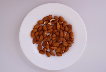 Almonds on white plate. Almond seeds, nuts.
