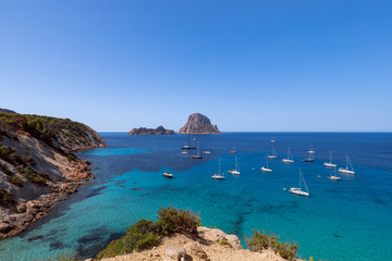 Fototapeta na wymiar Beautiful panoramic view of the mountain Es Vedra and sea sailing yachts. Ibiza, Balearic Islands, Spain