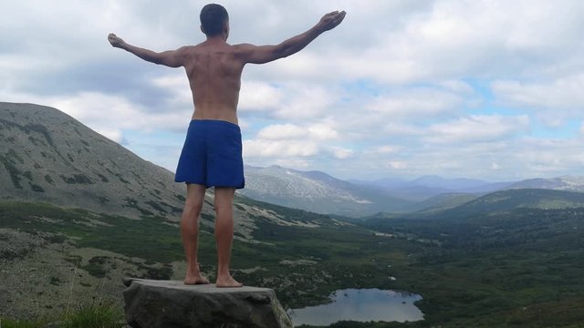 man stands on top of a mountain with open hands. at the top of the mountain, a man with his arms spread wide.
